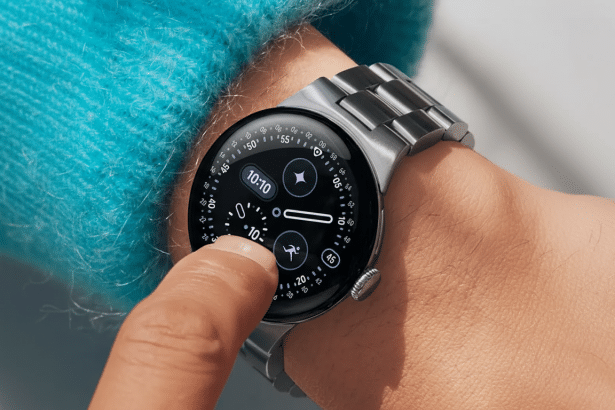 A close-up shot of a persons wrist wearing a silver smartwatch with a black face, displaying various icons and numbers. The persons finger is touching the screen.