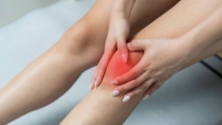 Eine Frau hält sich ihr Knie vor Schmerzen.